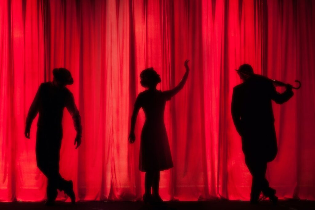 Silhouette of performers in front of curtain